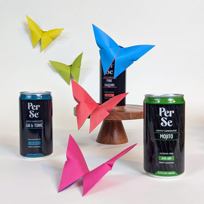 Per Se cocktail cans with colorful paper butterflies on a white background